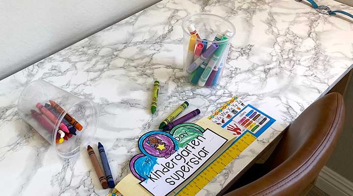 closeup of faux marble tabletop with kids crayons and coloring activity on top